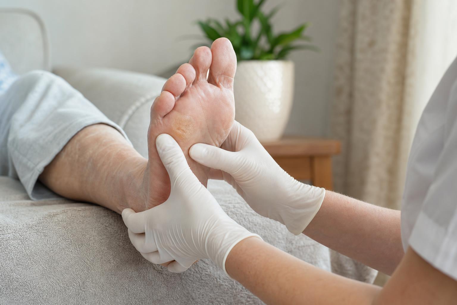 A practitioner gently checking hard skin under the forefoot during a home foot care visit