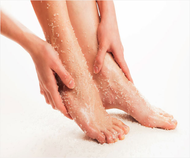 Close up of dry cracked heel skin being cared for with a foot scrub