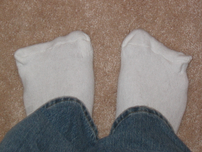 Feet in socks on a carpet, showing the everyday setting where odour from feet or footwear may first be noticed